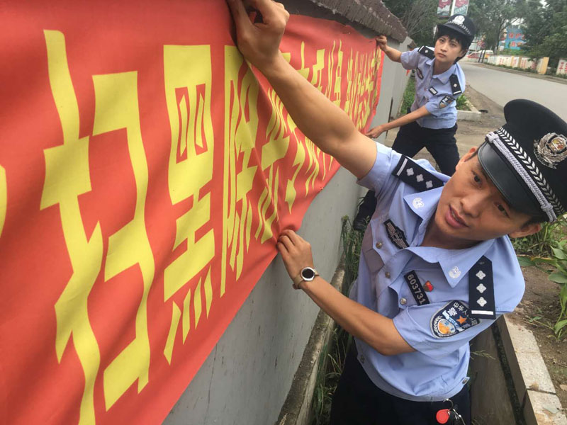 丹東市公安局振安分局同興派出所民警在懸掛掃黑除惡宣傳標(biāo)語橫幅。