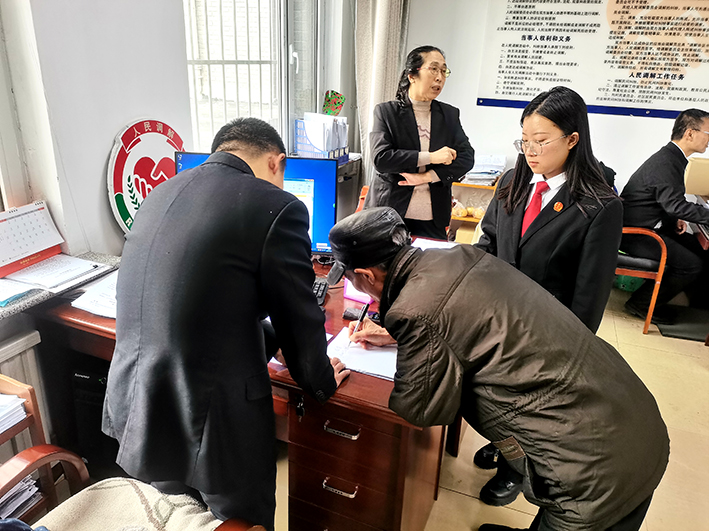 當(dāng)事人秦某（左二）在調(diào)解員張海川（左一）及工作人員的指導(dǎo)下，寫下確認(rèn)收到賠償?shù)恼f(shuō)明