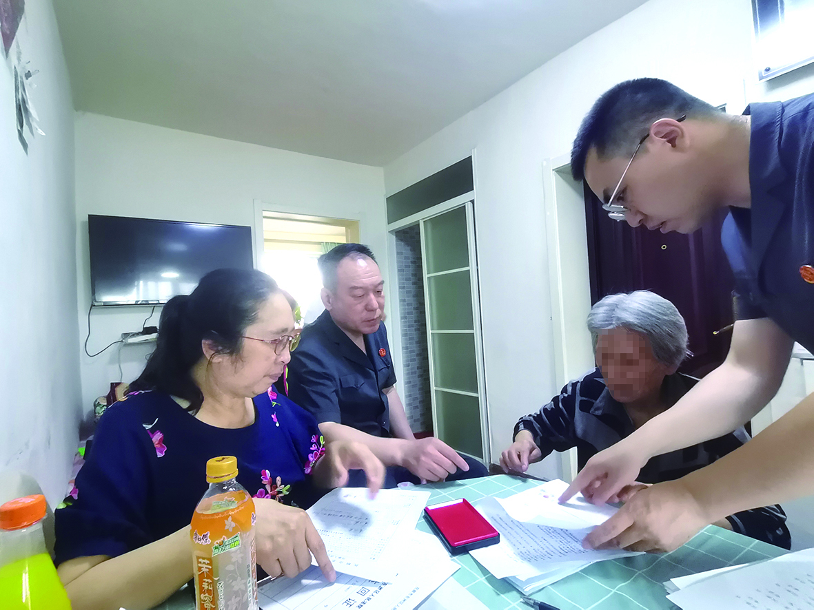 付承志（右一）胡善福（左二）指導(dǎo)潘某榮（右二）在調(diào)解書上簽字、按手印