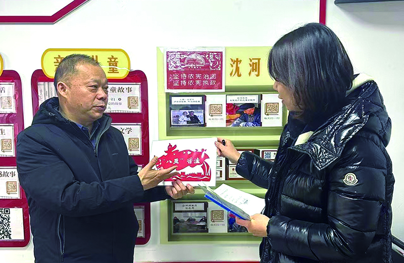 陳建國（左）向記者介紹社區(qū)以法治守護“一老一小”的普法活動內(nèi)容