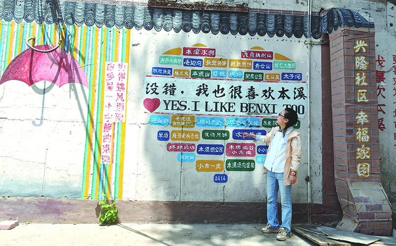 楊軼達(dá)向記者介紹社區(qū)的墻繪,。