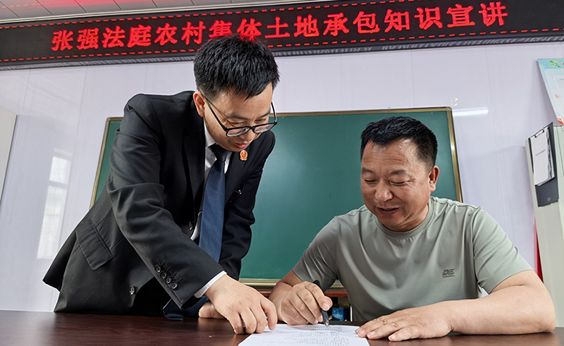 張強(qiáng)人民法庭庭長(zhǎng)田芝濤（左）指導(dǎo)村民如何填寫“普法清單”